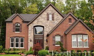 Very large brick and stone home with landscaped flowers and shrubs