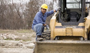 Builder standing on bulldozer representing contractors equipment insurance