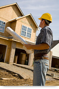 Hard hat wearing builder looking at partially constructed house