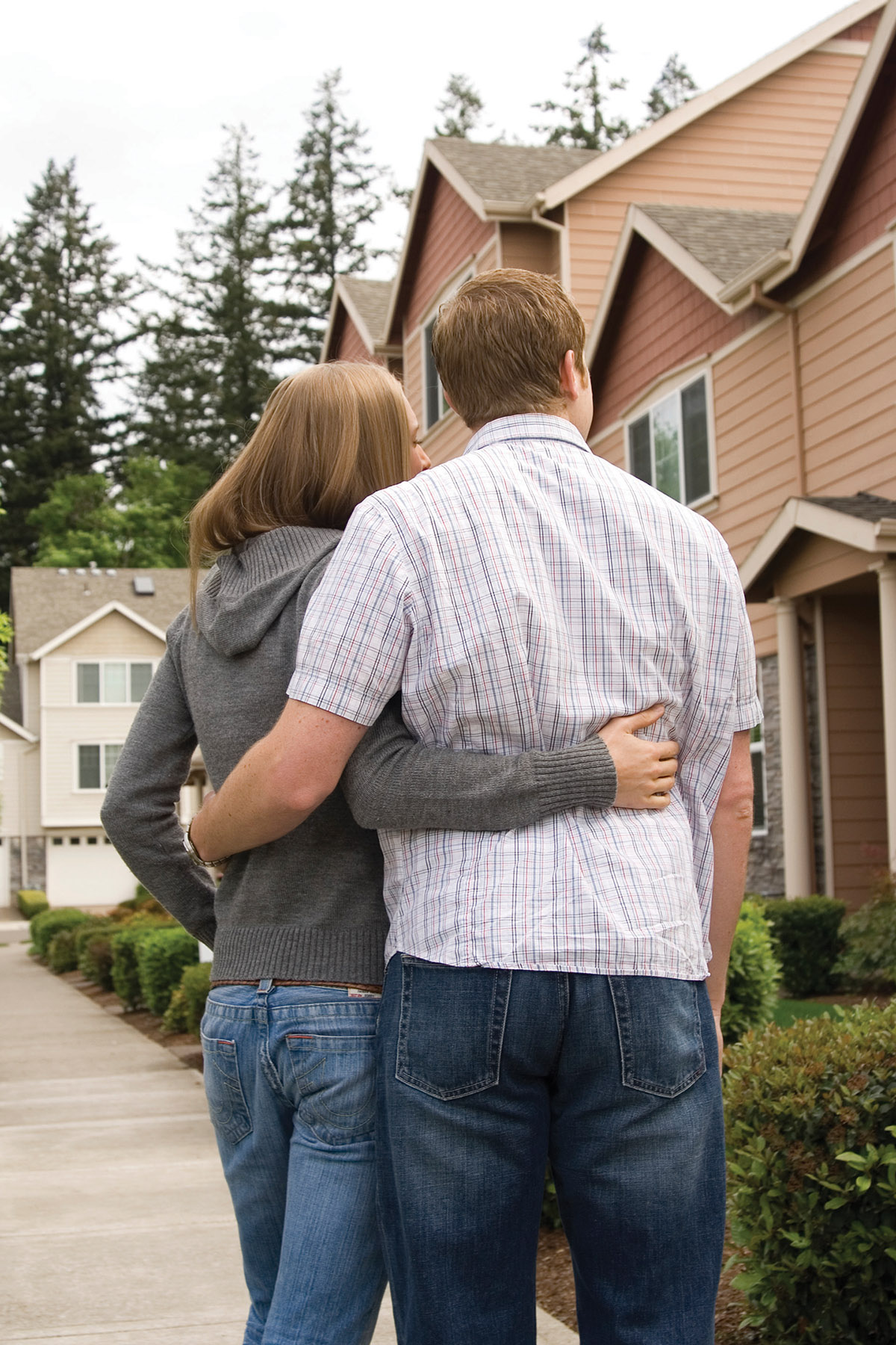 man and woman standing on sidewalk looking at house exterior