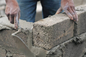 Builder using cement on concrete wall for building a new home